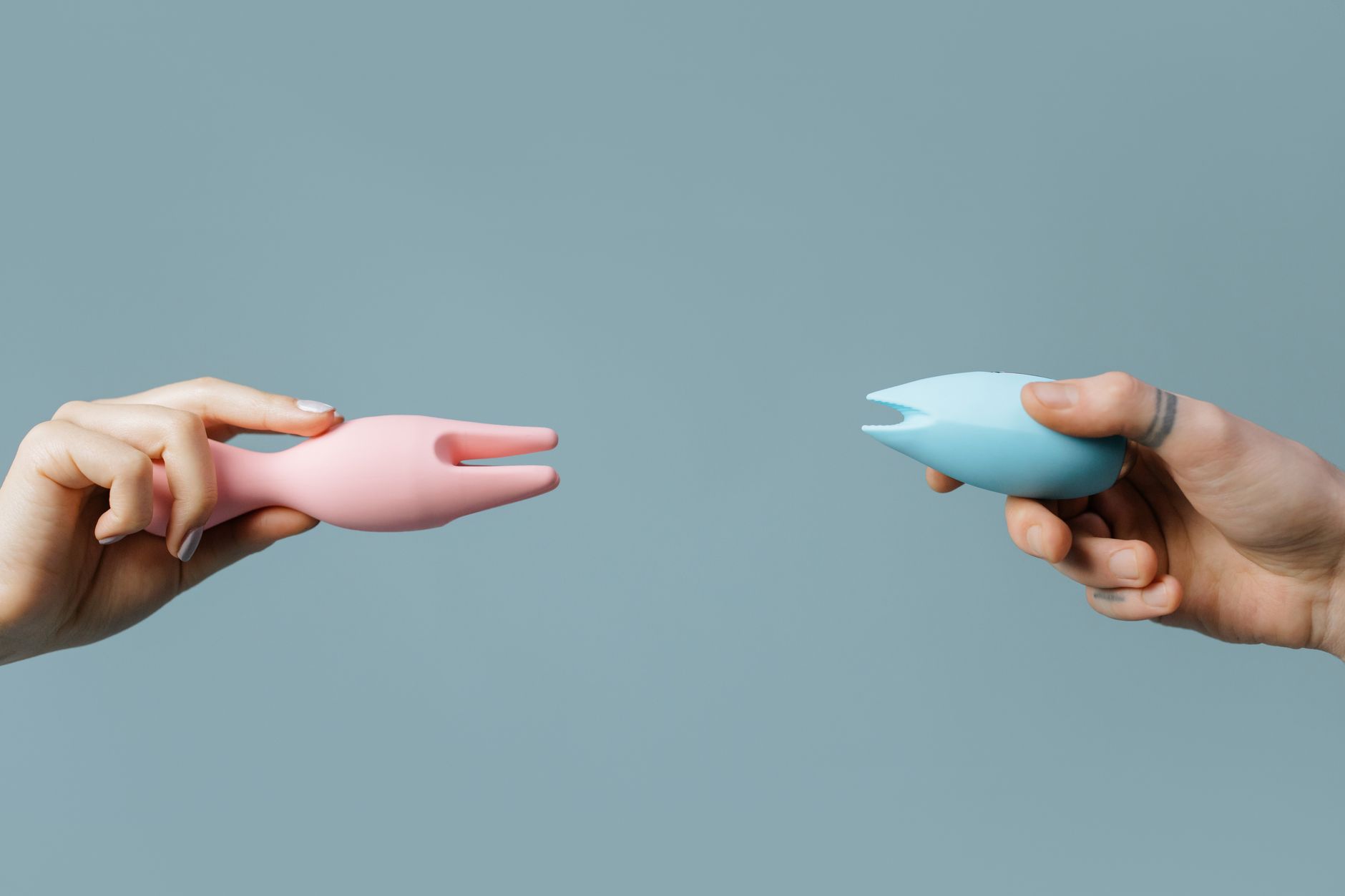 Two hands exploring pleasure with a vibrator against a calm background
