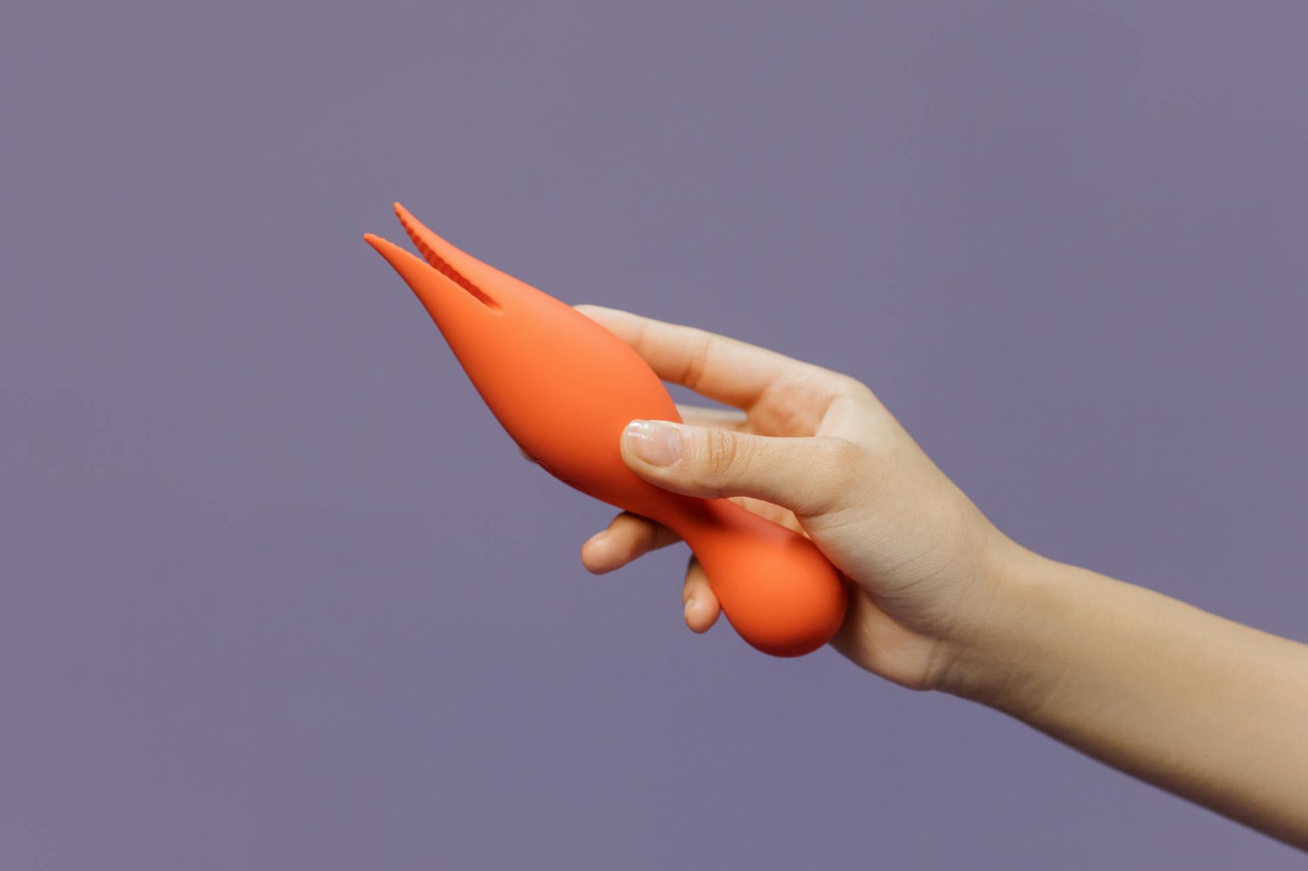 A hand holding a lemon vibrator against a minimalistic purple backdrop, showcasing sensuality without pressure