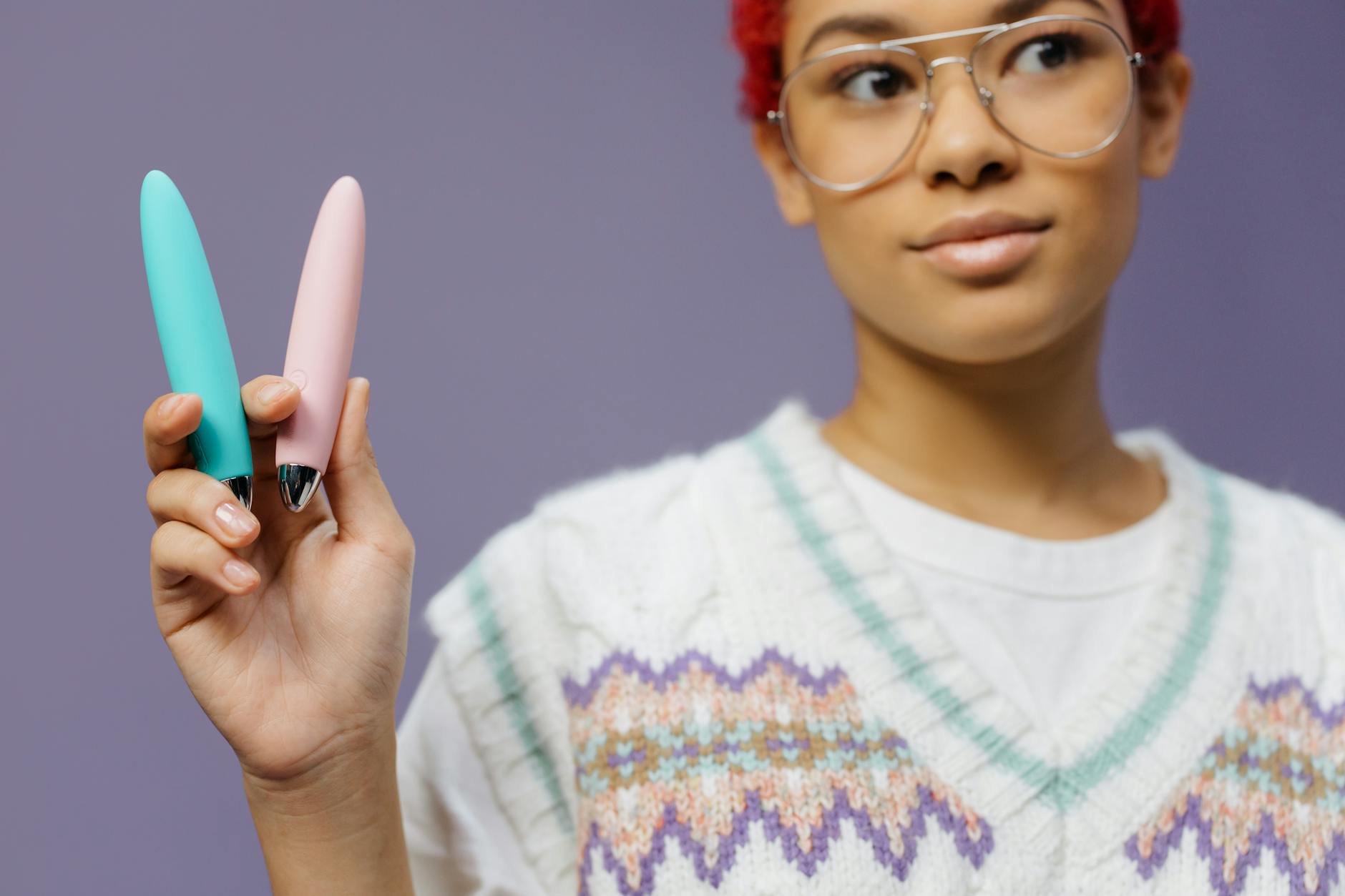A woman holds two colorful vibrators against a purple background, representing different lemon clitoral vibrator options.