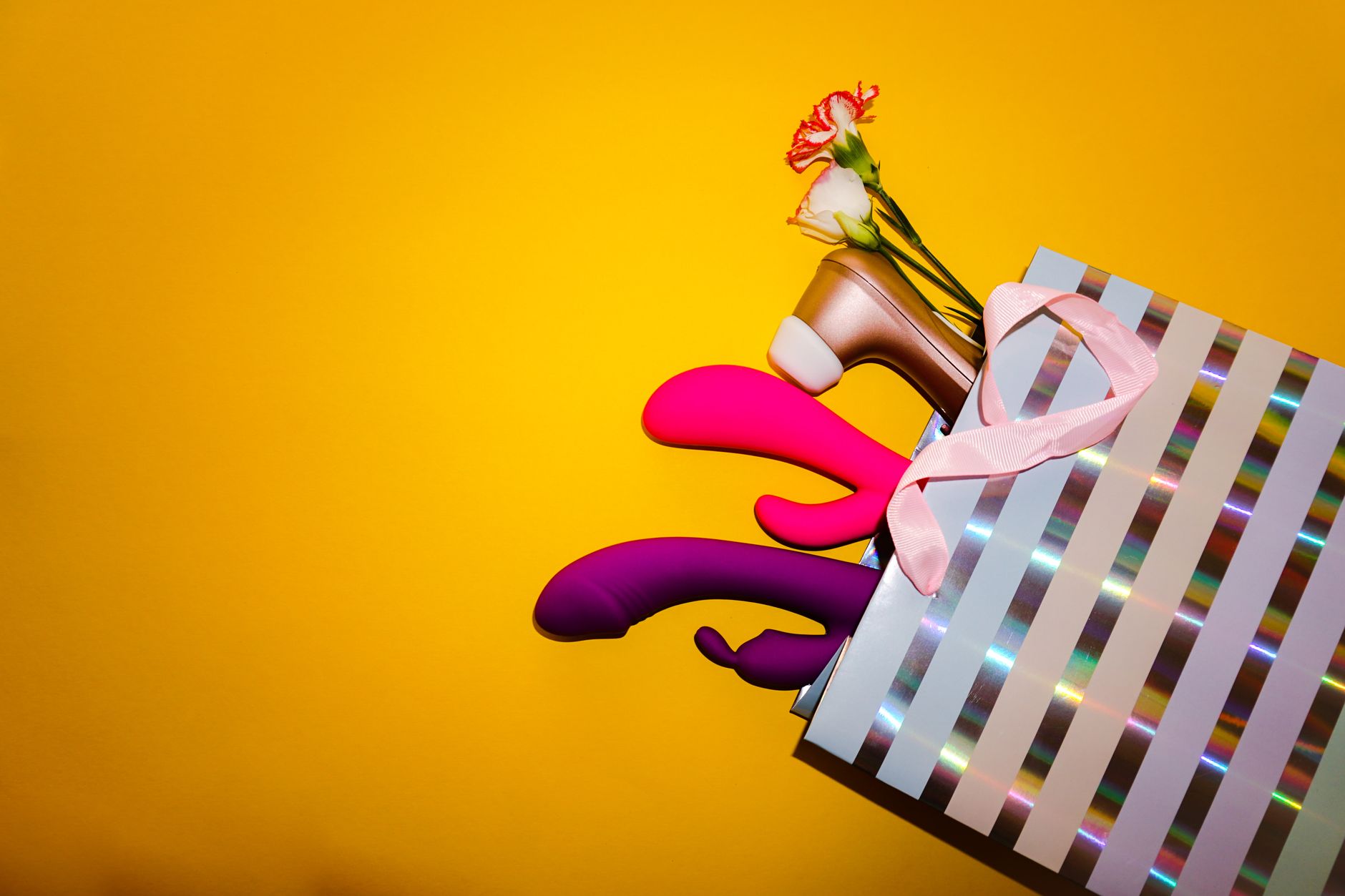 Hand holding a blue silicone vibrator against a purple background, representing modern sexual wellness.