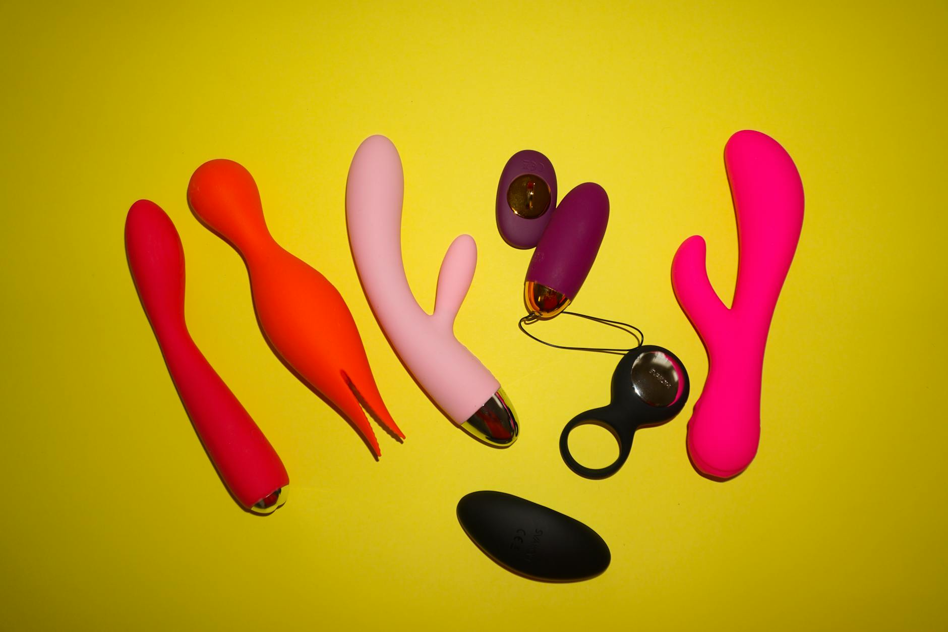 Hands holding silicone vibrators against a soft pastel background